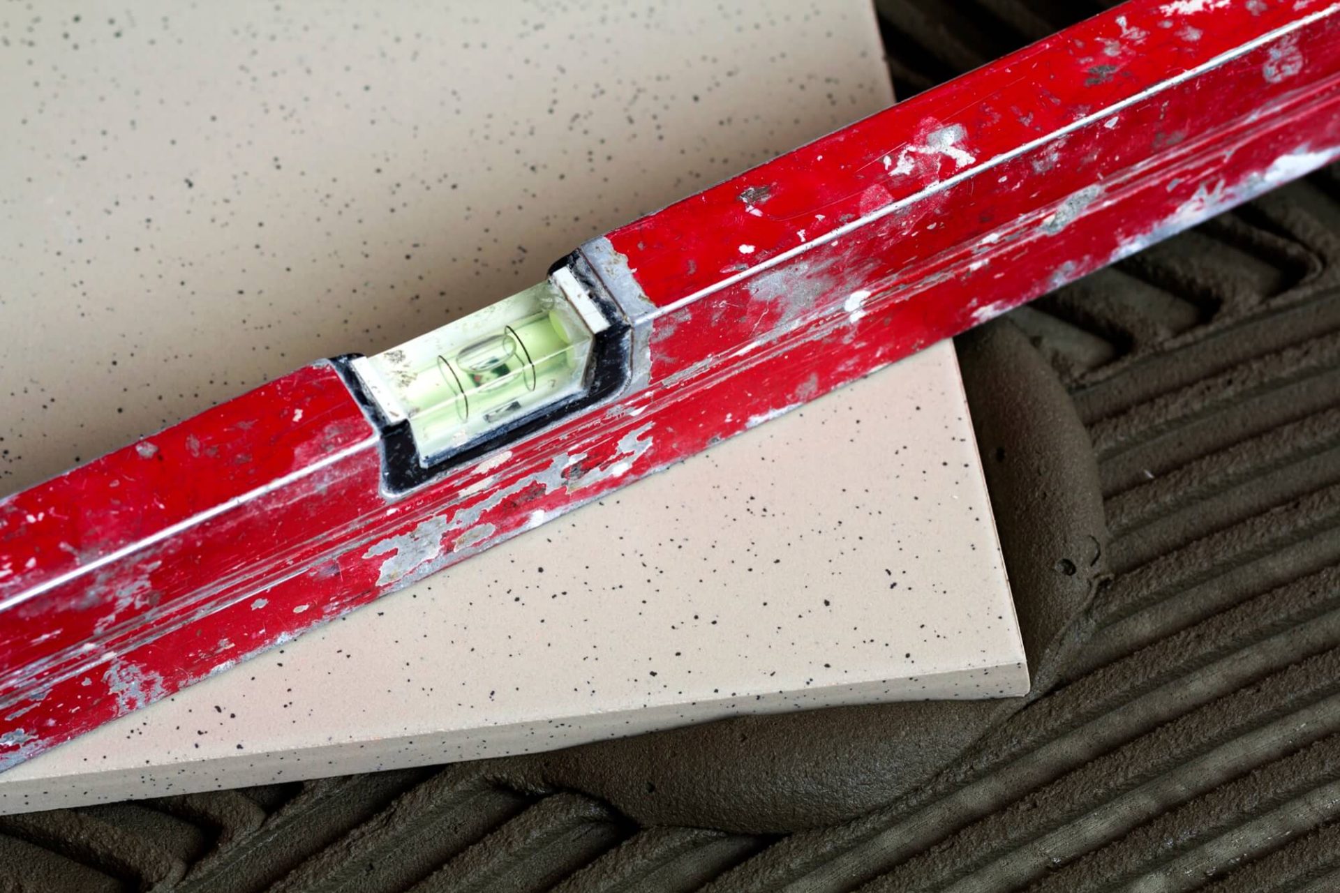 Steg-för-steg kakelsättning där vattenpass används för noggrannhet.